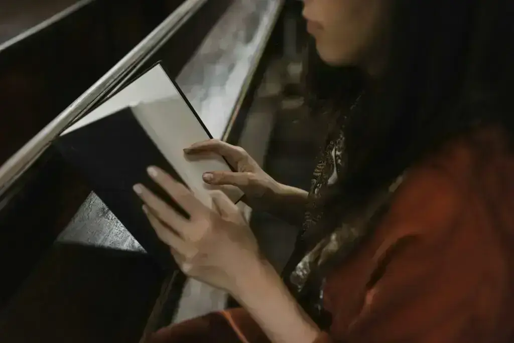 woman in orange long sleeve shirt holding white and black book