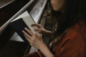 woman in orange long sleeve shirt holding white and black book