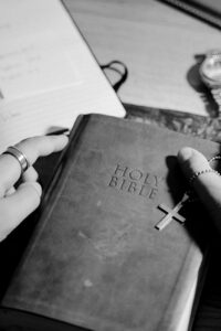 grayscale photo of a person holding a holy bible